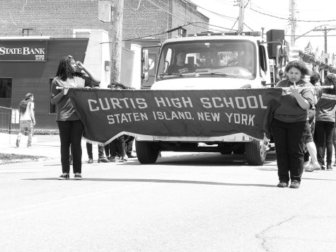 Warriors marching alongside the marching band float  holding little American Flags that they gave to spectators.