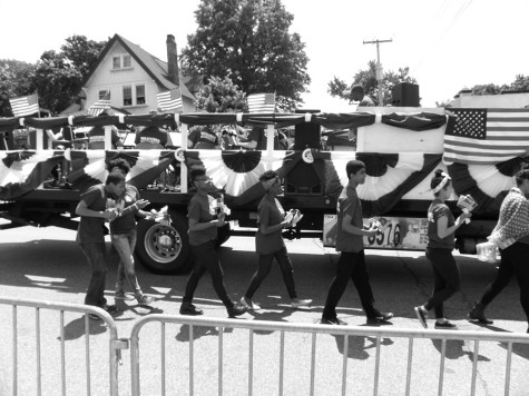 Warriors marching alongside the marching band float  holding little American Flags that they gave to spectators.